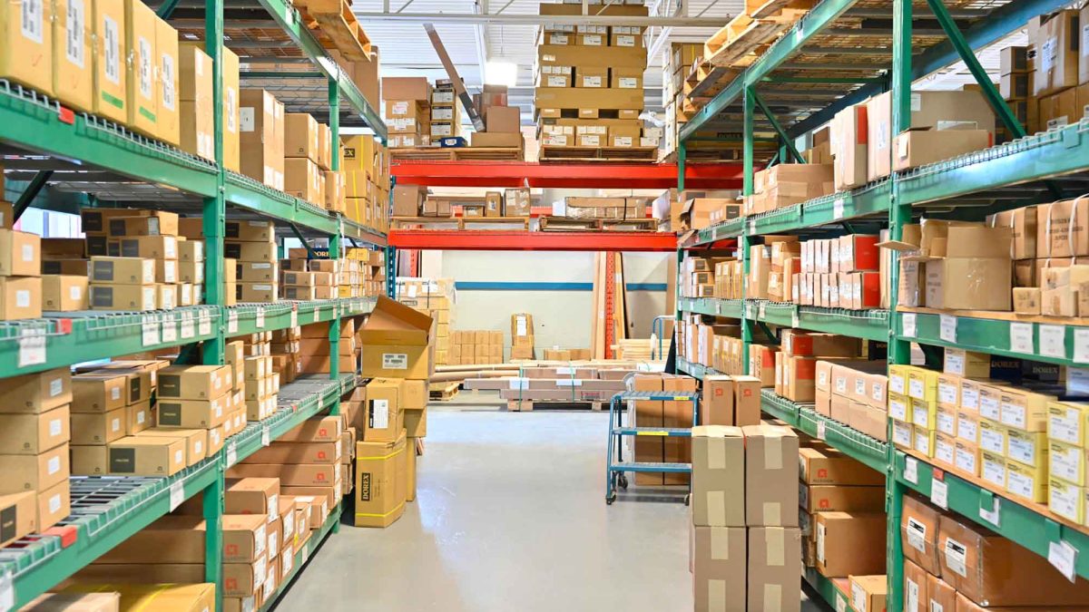 Rayonnages de l’entrepôt Raymond Architectural remplis de boîtes de quincaillerie et matériel pour portes et cadres – Raymond Architectural