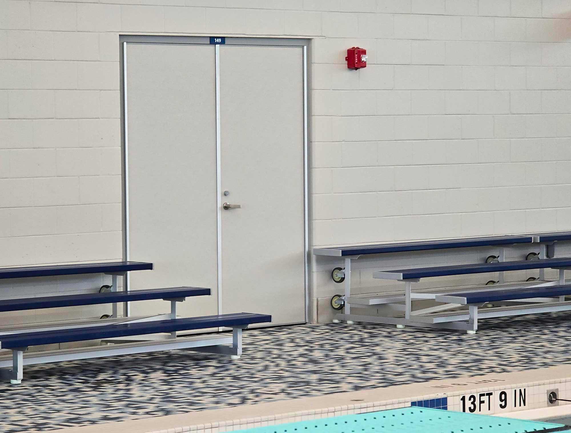 Porte architecturale double en acier installée dans un centre aquatique derrière les gradins de piscine – Raymond Architectural