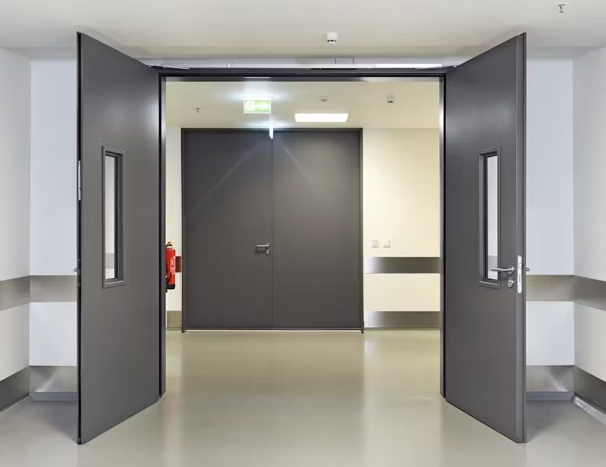 Portes architecturales coupe-feu en acier gris à double vantail avec vitrage, installées dans un corridor hospitalier – Raymond Architectural