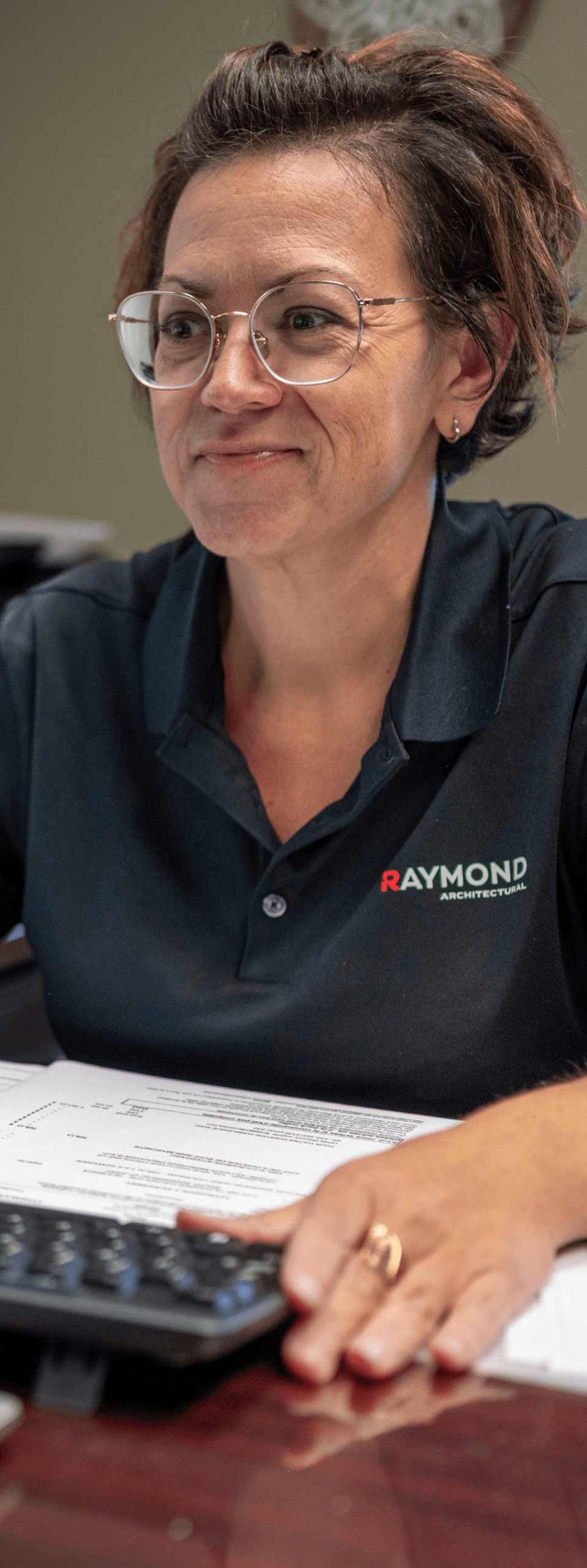 Employée de Raymond Architectural souriante travaillant à son bureau sur la gestion de projets architecturaux – Raymond Architectural